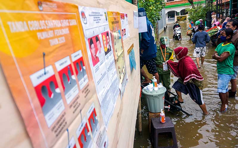 Warga antre untuk menggunakan hak pilihnya di Tempat Pemungutan Suara (TPS) 11 yang terendam banjir di Dukuh Clumprit, Degayu, Pekalongan, Jawa Tengah, Rabu (9/12/2020). Sebanyak lima TPS di dukuh tersebut terendam banjir akibat hujan deras sejak tiga hari terakhir, namun tidak menyurutkan warga untuk menggunakan hak pilihnya dalam Pilkada serentak 2020 di tengah masih merebaknya wabah Covid-19. ANTARA FOTO/Harviyan Perdana Putra