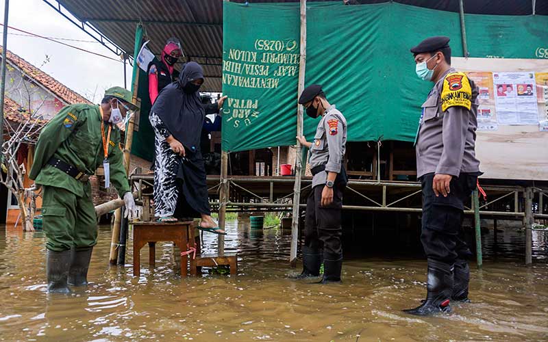 Warga berjalan turun dari panggung Tempat Pemungutan Suara (TPS) 11 yang terendam banjir usai menggunakan hak pilihnya di Dukuh Clumprit, Degayu, Pekalongan, Jawa Tengah, Rabu (9/12/2020). Sebanyak lima TPS di dukuh tersebut terendam banjir akibat hujan deras sejak tiga hari terakhir, namun tidak menyurutkan warga untuk menggunakan hak pilihnya dalam Pilkada serentak 2020 di tengah masih merebaknya wabah Covid-19. ANTARA FOTO/Harviyan Perdana Putra