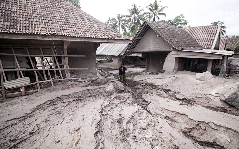 Warga melintas di rumah yang rusak akibat abu vulkanik letusan Gunung Semeru di Desa Sumber Wuluh, Lumajang, Jawa Timur, Minggu (5/12/2021). Akibat letusan Gunung Semeru tersebut sedikitnya puluhan rumah rusak. ANTARA FOTO/Umarul Faruq