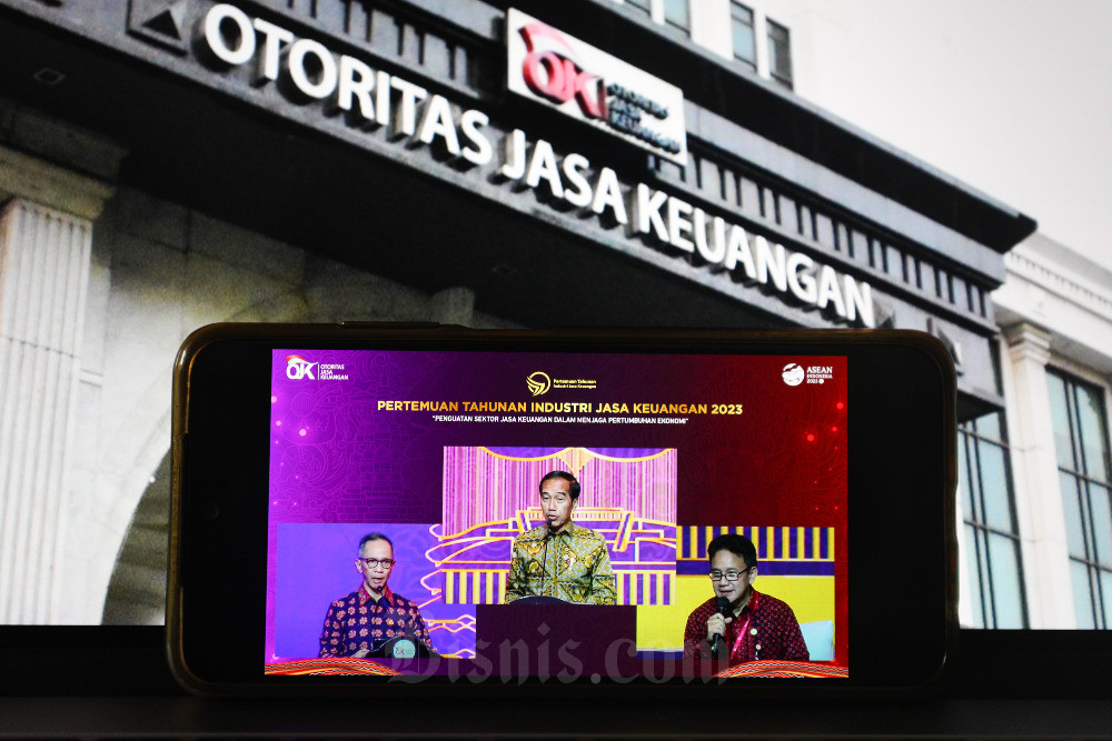 Layar menampilkan Presiden Joko Widodo (tengah), Ketua Dewan Komisioner Otoritas Jasa Keuangan (OJK) Mahendra Siregar (kiri) dan Wakil Ketua Dewan Komisioner OJK Mirza Adityaswara saat memberikan pemaparan dalam acara Pertemuan tahunan industri jasa keuangan (PTIJK) 2023 dengan tema Penguatan sektor jasa keuangan dalam menjaga pertumbuhan ekonomi, Jakarta, Senin (6/2/2023). PTIJK 2023 merupakan puncak acara dari rangkaian agenda OJK bersama industri jasa keuangan pada Desember 2022. Melalui agenda ini, Presiden Jokowi bersama OJK menyampaikan pesan strategis kepada industri dan stakeholder jasa keuangan sebagai upaya untuk menjaga pertumbuhan ekonomi. Bisnis/Suselo Jati