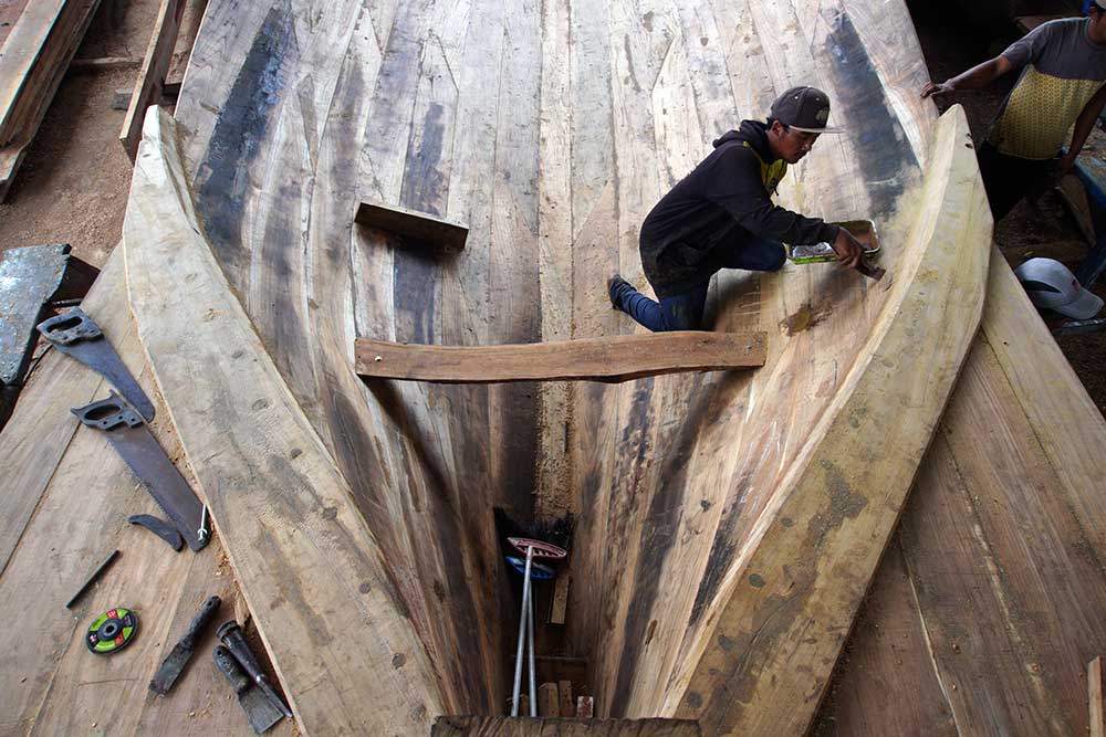 Pekerja menyelesaikan pembuatan kapal nelayan tradisional di Tambakrejo, Sumbermanjing Wetan, Malang, Jawa Timur, Rabu (15/3/2023). Pembuatan kapal nelayan berkapasitas 40 ton yang biasanya dikerjakan selama tiga bulan dengan biaya sekitar RP600 juta itu kini menghabiskan waktu enam bulan dengan biaya Rp800 juta per kapal yang disebabkan sulitnya mendapatkan bahan baku berupa kayu jati berkualitas. ANTARA FOTO/Irfan Sumanjaya