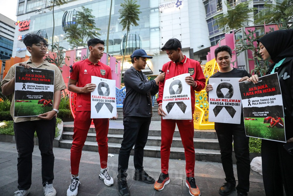 Anggota komunitas CentennialZ memasangkan pita hitam kepada para pemain Timnas Indonesia U-20 Arkhan Kaka (ketiga kanan) dan Aditya Nugraha (kedua kiri) saat aksi gerakan 1 juta pita hitam di Jakarta, Jumat (31/3/2023). Aksi tersebut sebagai bentuk ekspresi duka atas dicoretnya Indonesia sebagai tuan rumah Piala Dunia U-20 2023, serta untuk memberikan semangat kepada para pemain Timnas Indonesia U-20 yang berduka karena batal berlaga di Piala Dunia U-20 2023. Bisnis/Arief Hermawan