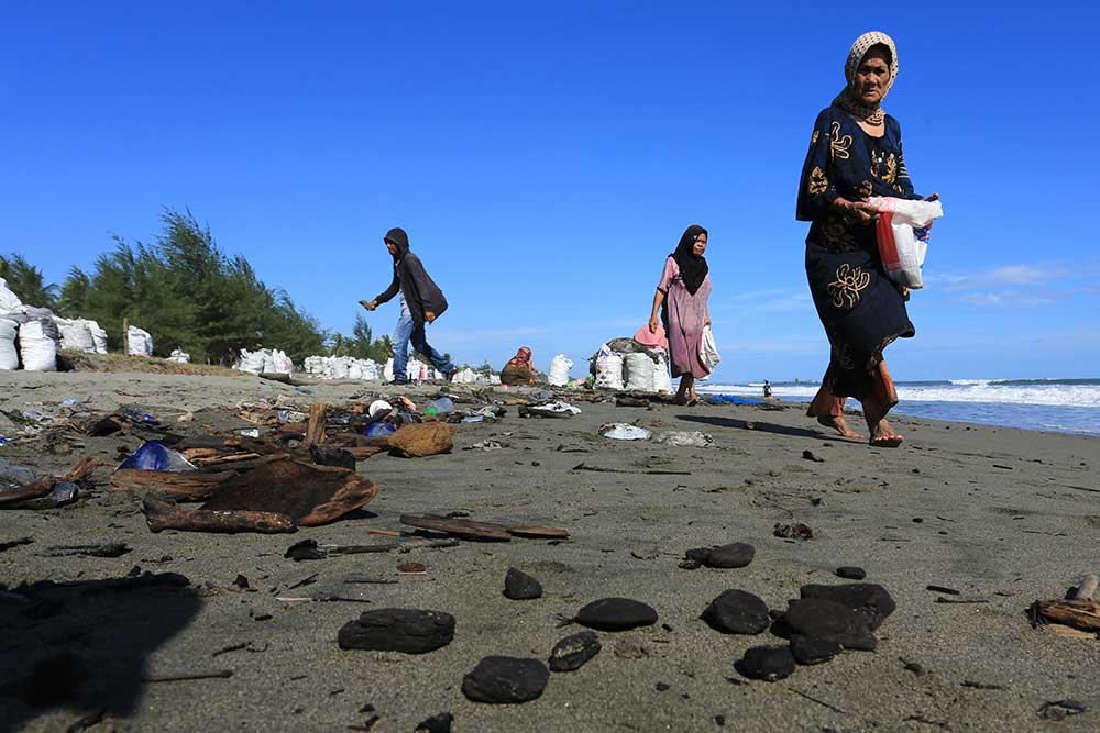 Sejumlah warga mengumpulkan batu bara yang mencemari kawasan pesisir pantai di Desa Peunaga Pasi, Meureubo, Aceh Barat, Aceh, Senin (29/5/2023). Limbah batu bara yang kerap mencemari kawasan pantai tersebut dikumpulkan masyarakat setempat yang selanjutnya diambil oleh salah satu perusahaan eksploitasi batu bara dengan memberi upah Rp25.000 per karung ukuran 50 kilogram. ANTARA FOTO/Syifa Yulinnas