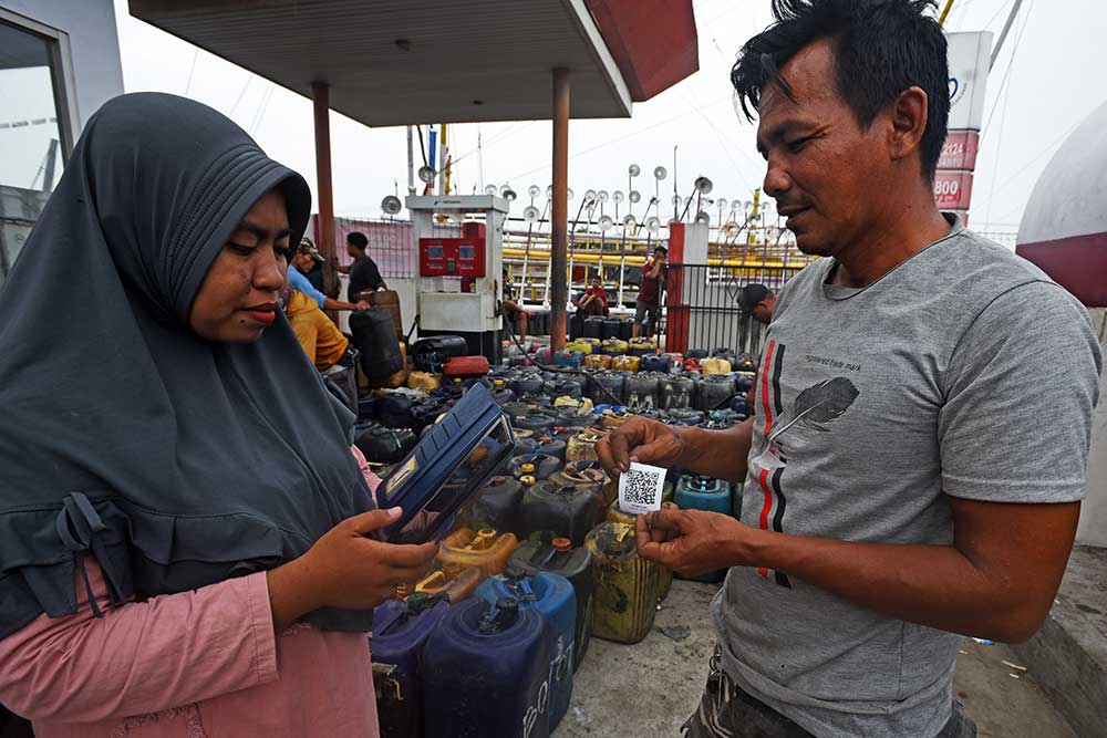 Petugas SPBU (kiri) menjelaskan cara menggunakan aplikasi pembelian solar pada telepon seluler kepada nelayan di Pelabuhan Perikanan Karangantu Kota Serang, Banten, Kamis (8/6/2023). PT Pertamina menekankan pentingnya penggunaan aplikasi dalam penyaluran BBM bersubsidi untuk nelayan agar tepat sasaran dan mencegah penyimpangan. ANTARA FOTO/Asep Fathulrahman