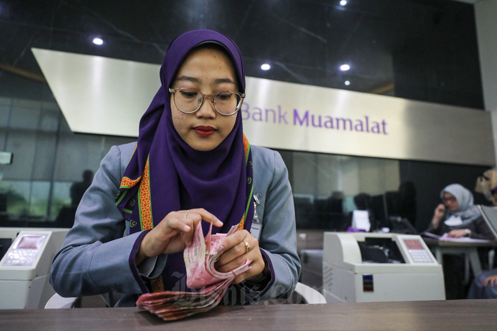 Karyawati melayani nasabah di kantor Bank Muamalat di Jakarta, Senin (18/9/2023).rnPT Bank Muamalat Indonesia Tbk. menargetkan pembiayaan konsumer dapat tumbuh hingga lebih dari 130% pada akhir 2023, antara lain dengan mendorong Kredit Perumahan Rakyat (KPR) melalui program KPR Hijrah Baitullah. Bisnis/Arief Hermawan P
