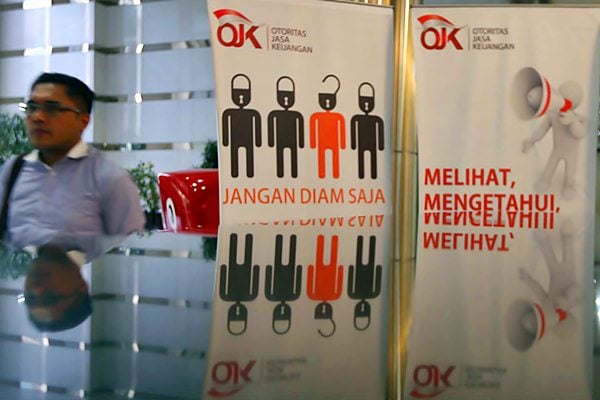 Karyawan melintas di dekat logo Otoritas Jasa Keuangan (OJK) di Jakarta./JIBI-Nurul Hidayat