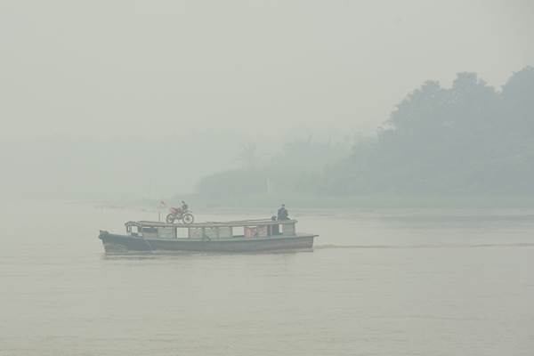 Sebuah kapal motor melintasi Sungai Kapuas yang diselimuti kabut asap tebal di Kabupaten Kubu Raya, Kalbar, Jumat (25/9)./Antara
