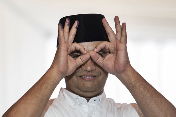 Anies Baswedan meneropong menggunakan tangan usai memberikan hak pilih pada Pemilihan Gubernur di TPS 28 Cilandak Barat, Jakarta, Rabu (19/4)./Antara-M Agung Rajasa