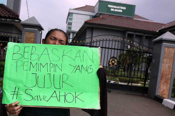 Seorang pendukung Basuki Tjahaja Purnama atau Ahok membentangkan poster saat berunjuk rasa di depan gedung Pengadilan Tinggi DKI Jakarta di Jakarta Pusat, Sabtu (13/5). Mereka menuntut Pengadilan Tinggi DKI Jakarta menandatangani surat penangguhan penahanan Ahok. ANTARA FOTO/Galih Pradipta/Antara