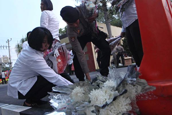 Dua personel polisi meletakkan bunga di sekitar lokasi penyerangan di Polda Sumut, Medan, Sumatera Utara, Senin (26/6). Aksi belasungkawa tersebut untuk mengenang almarhum Aiptu Martua Sigalingging yang tewas saat bertugas dalam aksi penyerangan terduga teroris di Polda Sumut. ANTARA FOTO/Septianda Perdana