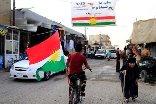 Seorang bocah mengendarai sepeda sambil membawa bendera Kurdistan di Tuz Khurmato, Irak, pada Minggu (24/9/2017)./Reuters- Thaier Al-Sudani