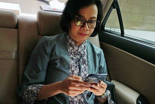 Menteri Keuangan Sri Mulyani Indrawati membuka ponsel pintarnya saat berada di dalam mobilnya, Jumat (13/1/2017)./Bloomberg-Dimas Adrian