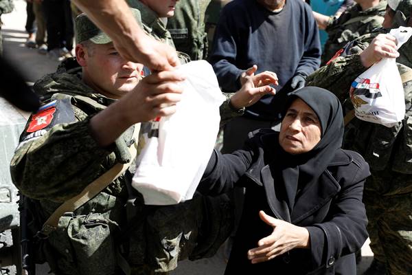 Seorang wanita yang melarikan diri dari Ghouta timur menerima bantuan dari pasukan Rusia di sebuah tempat penampungan di Adra, dekat Damaskus, Suriah, 20 Maret 2018./Reuters