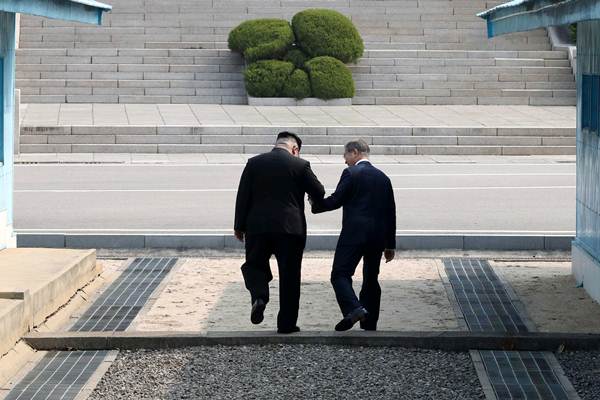 Pemimpin Korea Utara Kim Jong Un (kiri) bergandengan tangan dengan Presiden Korea Selatan Moon Jae-in saat pertemuan di desa gencatan senjata Panmunjom, Korea Selatan, Jumat (27/4/2018)./Reuters