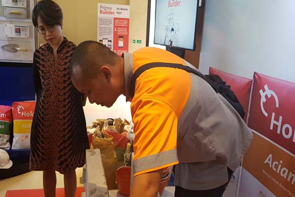 Head of Costumer Marketing PT Holcim Indonesia Tbk Johanna Daunan (kiri) melihat staf perusahaan tersebut mendemontrasikan penggunaan semen mortar pada pemasangan bata ringan di sela-sela Peluncuran Produk Mortar Andalan di Malang, Kamis (1/11/2018)/Bisnis-Choirul Anam