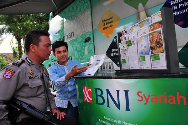 Ilustrasi - Seorang pegawai menjelaskan layanan perbankan kepada seorang petugas polisi di Bus Layanan Gerak BNI Syariah, di Kota Pekanbaru, Rabu (20/5)./Antara