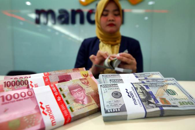Karyawati Bank Mandiri menghitung mata uang dolar AS dan rupiah di Jakarta, Selasa (12/2/2019)./Bisnis-Abdullah Azzam