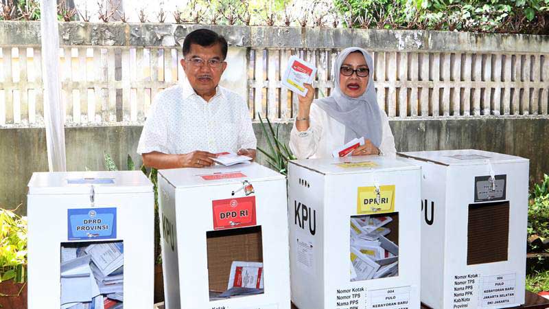 Wakil Presiden Jusuf Kalla (kiri) didampingi Istri Mufidah Jusuf Kalla (kanan) bersiap memasukan surat suara ke dalam kotak suara seusai menggunakan hak pilih pada Pemilu 2019 di TPS 04 Kebayoran Baru, Jakarta, Rabu (17/4/2019)./ANTARA-Reno Esnir