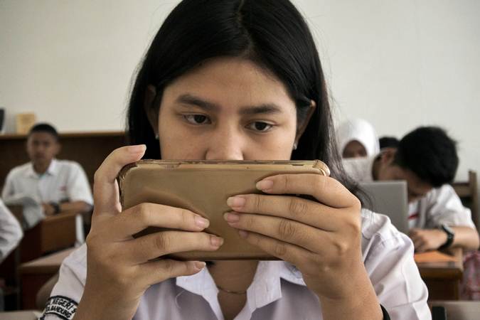 Siswi menggunakan gawai saat mengerjakan soal UASBN 2019 di SMA Negeri 9 Kota Bandung, Jawa Barat, Senin (18/3/2019). SMA Negeri 9 Kota Bandung tersebut mulai menerapkan penggunaan teknologi smart router dalam pelaksanaan UASBN./ANTARA-Novrian Arbi