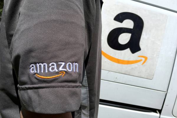 Seorang pengemudi Amazon.com Inc berdiri di samping truk di Los Angeles, California, Amerika Serikat./Reuters
