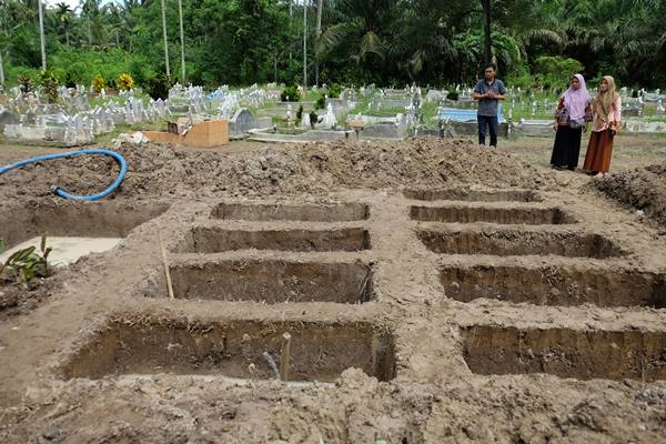 Warga melihat liang kubur yang telah disiapkan untuk pemakaman korban kebakaran pabrik korek api gas (mancis) di perkuburan muslim, Desa Sambirejo, Langkat, Sumatera Utara, Minggu (23/6/2019). /Antara