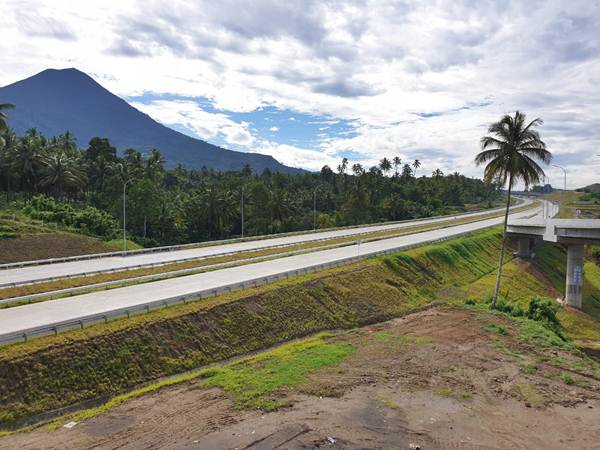 Suasana jalan tol Manado-Bitung dengan latar belakang Gunung Klabat pada Jumat (5/7/2019). Keberadaan jalan tol ini diharapkan memacu investasi di Sulawesi Utara terutama di KEK Bitung./Bisnis-Lukas Hendra
