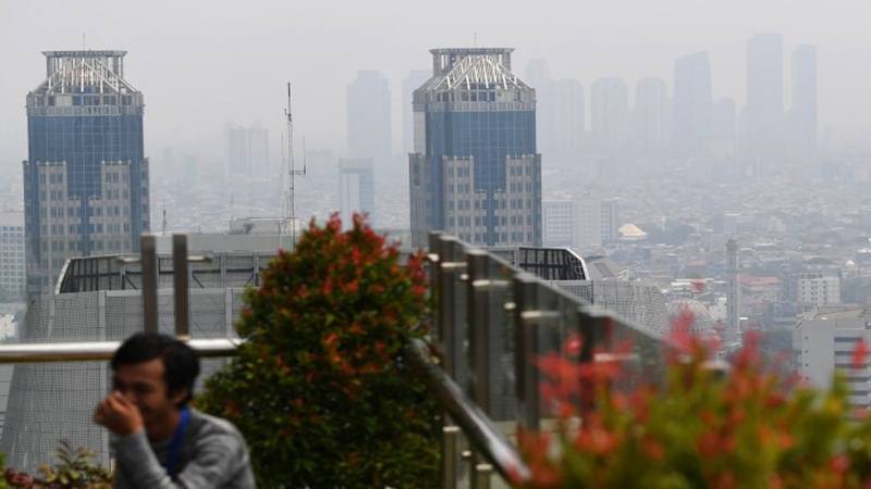 Warga beraktivitas dengan latar belakang suasana gedung bertingkat yang diselimuti asap polusi di Jakarta, Senin (29/7/2019). /Antara