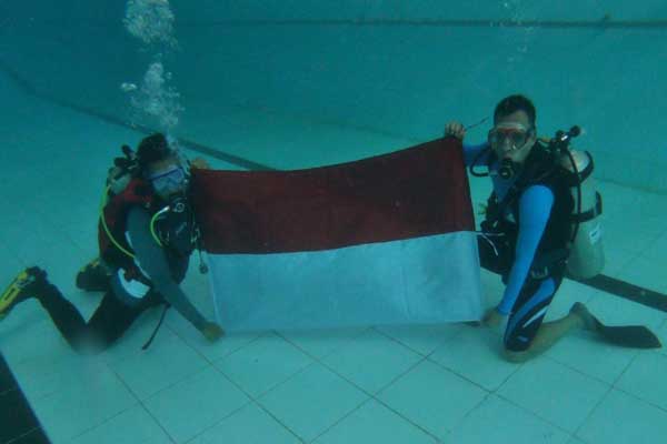Bupati Kabupaten Batang Wihaji saat mengibarkan Bendera Merah Putih dibawah air/istimewa)