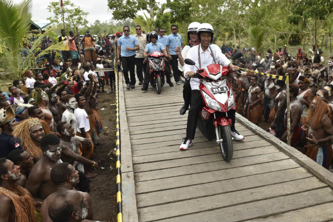 Presiden Joko Widodo berboncengan dengan Ibu Negara Iriana Joko Widodo menggunakan motor listrik menyapa warga Asmat saat kunjungan kerja di Kampung Kaye, Distrik Agats, Kabupaten Asmat, Papua, Kamis (12/4/2018)./Antara-Puspa Perwitasari