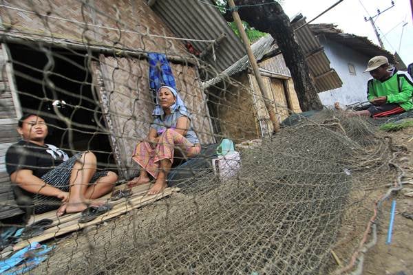 Nelayan (kanan) memperbaiki jaring di halaman rumahnya di desa Singaraja, Indramayu, Jawa Barat, Kamis (23/2)./Antara-Dedhez Anggara