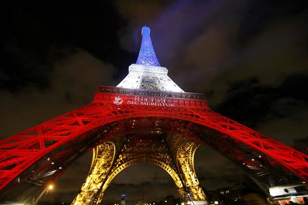 Menara Eiffel disinari lampur berwarna putih, merah dan biru sesuai warna bendera Prancis sebagai penghormatan kepada korban tewas serangan teroris di Paris, Jumat (13/11/2015)/Reuters