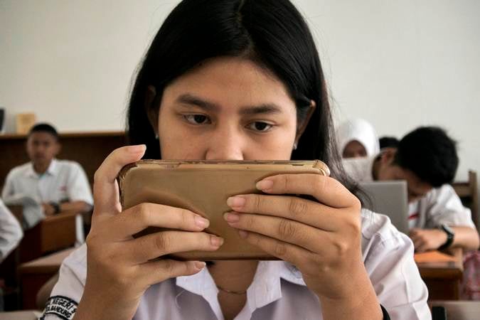 Seorang pelajar di sebuah SMA Negeri Kota Bandung, Jawa Barat, Senin (18/3/2019), tengah menggunakan smartphone. - ANTARA FOTO/Novrian Arbi