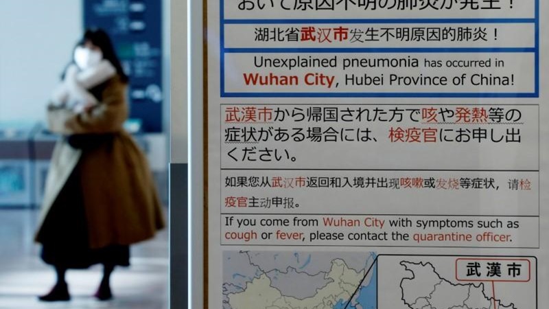 Seorang wanita mengenakan masker berjalan melewati papan pemberitahuan karantina tentang wabah virus corona di Wuhan, China di ruang kedatangan Bandara Haneda di Tokyo, Jepang, 20 Januari 2020./ REUTERS - Kim Kyung-Hoon