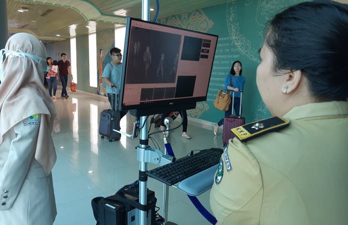 Petugas Kantor Pelabuhan Palembang memeriksa suhu tubuh penumpang di Bandara SMB II Palembang menggunakan thermal scanner./Bisnis - Dinda Wulandari