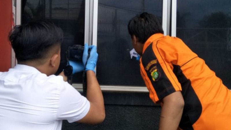Petugas Satuan Reserse Kriminal Polrestro Jakarta Timur memeriksa lubang di kaca ruang pelayanan administrasi Rutan Klas 1 Cipinang, Jakarta Timur, yang ditembak oleh orang tidak dikenal, Senin (10/2/2020)./Atara/Andi Firdaus)