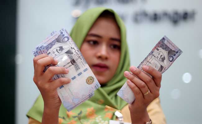Karyawan menunjukan mata uang Riyal di money changer./Bisnis-Abdullah Azzam