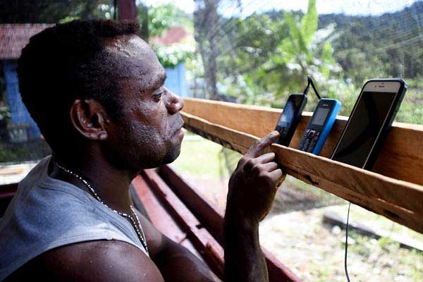 Warga menerima panggilan masuk melalui telepon genggamnya di pelosok Mosairo, Nabire, Papua, Selasa (11/7)./ANTARA-Indrayadi TH