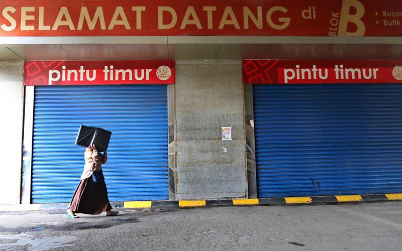 Warga berjalan melintasi Pasar Tanah Abang yang tutup di Jakarta, Senin (6/4/2020). Pemerintah Provinsi DKI Jakarta memperpanjang penutupan sementara Pasar Tanah Abang hingga Senin (19/4) sebagai bentuk pencegahan penyebaran COVID-19. Bisnis - Eusebio Chrysnamurti