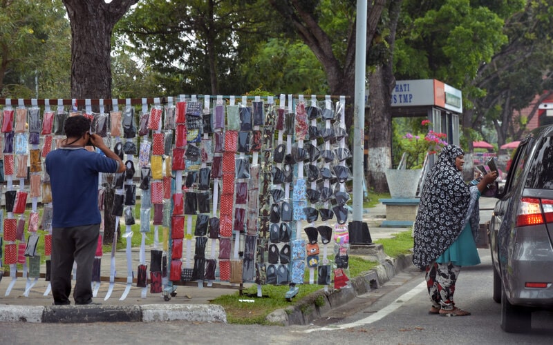 Sejumlah pedagang kaki lima menawarkan masker kain kepada pengguna jalan di Kota Pekanbaru, Riau, Selasa (7/4/2020). Penjual kaki lima menjual masker kain dan sarung tangan bermunculan di Kota Pekanbaru memanfaatkan langkanya masker saat wabah Covid-19 dengan harga jual berkisar Rp10.000 hingga Rp20.000 per helai./Antara-FB Anggoro.n