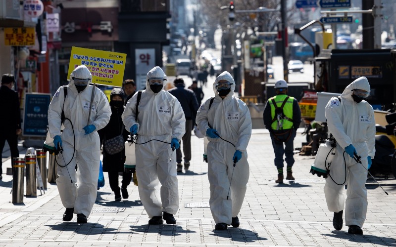 Tentara Korea Selatan mengenakan Alat Pelindung Diri (APD) sembari menyemprotkan disinfektan di jalanan Seoul, Korea Selatan, Kamis (5/3/2020)./Bloomberg-SeongJoon Cho