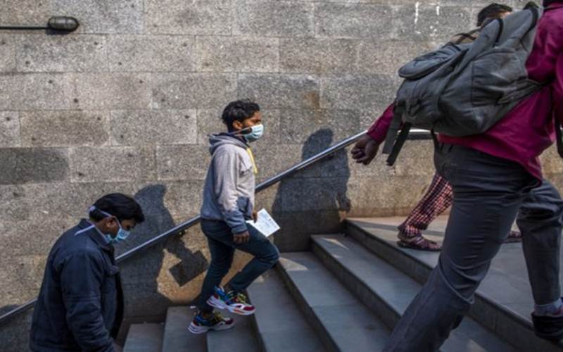 Warga di India berjalan sambil menggunakan masker pelindung/Bloomberg-Prashanth Vishwanathan
