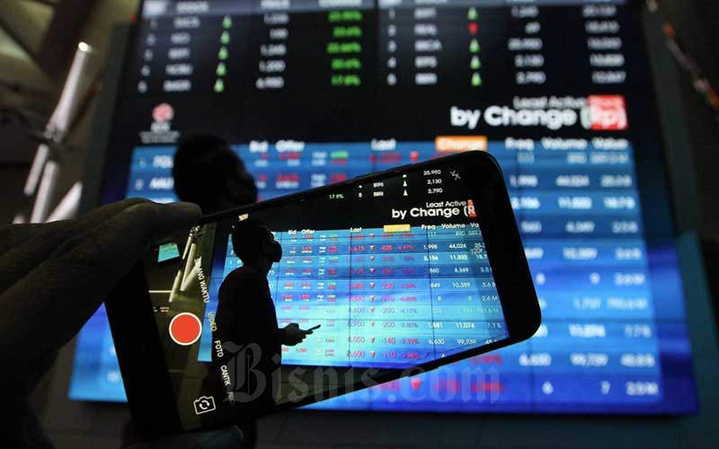 Pengunjung menggunakan smarphone didekat papan elektronik yang menampilkan perdagangan harga saham di Jakarta, Rabu (22/4/2020). Bisnis/Dedi Gunawan