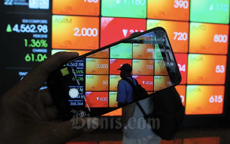 Pengunjung menggunakan smartphone didekat papan elektronik yang menampilkan perdagangan harga saham di Jakarta, Rabu (22/4/2020). Bisnis/Dedi Gunawan
