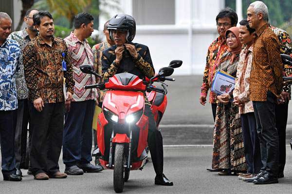 Presiden Joko Widodo mengenakan helm sebelum menjajal motor listrik buatan dalam negeri 'Gesits' seusai melakukan audiensi dengan pihak-pihak yang terkait produksi di halaman tengah Istana Kepresidenan, Jakarta, Rabu (7/11/2018)./ANTARA-Wahyu Putro A