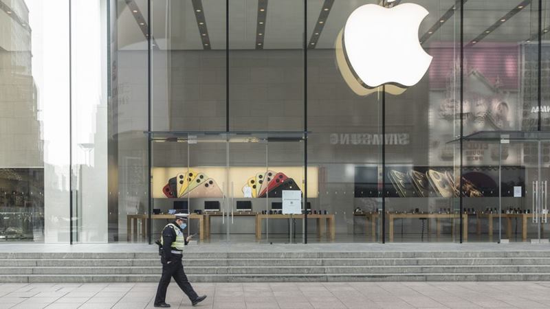 Seorang petugas polisi yang mengenakan masker pelindung berjalan melewati toko Apple yang tutup di Shanghai, China, pada 5 Februari 2020./ Qilai Shen - Bloomberg