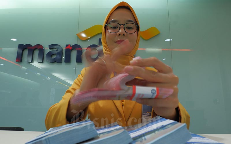 Karyawan menghitung uang pecahan Rp100.000 disalah satu kantor cabang milik PT Bank Mandiri (Persero) Tbk yang ada di Jakarta, Senin (7/10). Bisnis/Nurul Hidayat