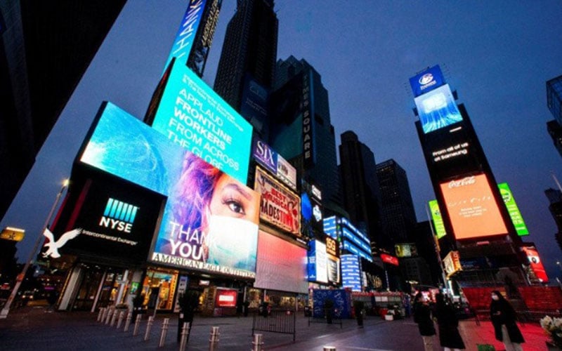 Warga berjalan di sekitar Times Square saat beberapa layar bercahaya biru sebagai bagian dari inisiatif Light It Blue untuk menghormati tenaga kesehatan, saat penyebaran penyakit virus corona (Covid-19) di New York, Amerika Serikat, Kamis (23/4/2020)./Antara/Reuters
