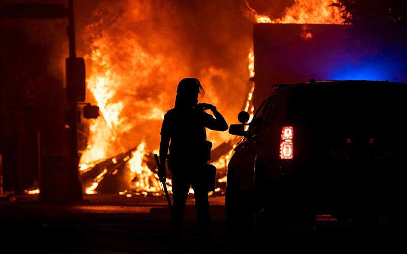Petugas berada di dekat api saat aksi protes atas kematian George Floyd di Minneapolis, Amerika Serikat, Senin (1/6/2020). Bloomberg/Getty Images/Stephen Maturen