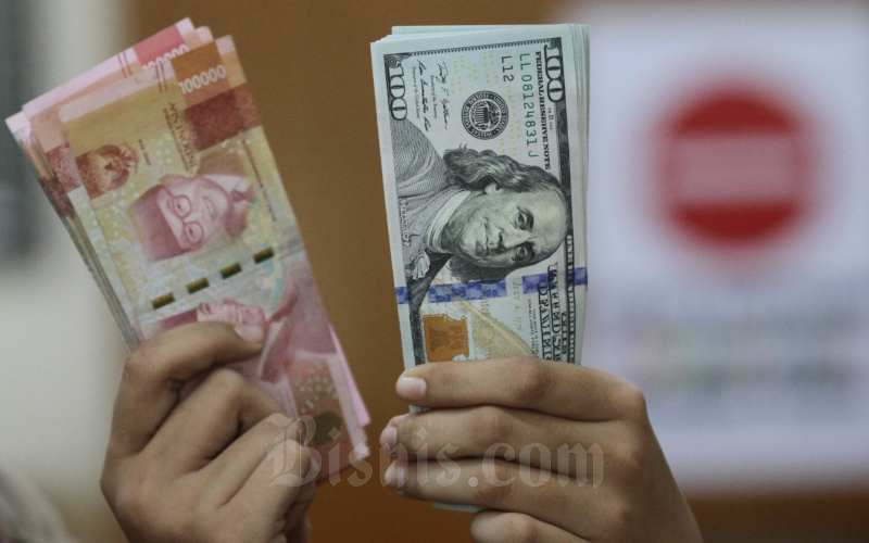 Karyawati menunjukan uang Rupiah dan dolar AS di salah satu gerai penukaran mata uang asing di Jakarta, Minggu (7/6/2020). Bisnis/Arief Hermawan P