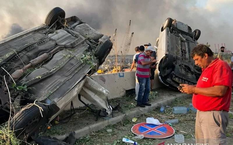 Warga berdiri di dekat mobil yang hancur akibat ledakan gudang bahan peledak di Beirut, Lebanon, Selasa (4/8/2020)./Antara-Reuters